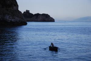 a man is rowing a boat in the water at Bed and Breakfast Da Claudio in Conca dei Marini