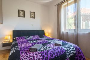 a bedroom with a bed with a purple blanket and a window at Apartments Sun in Zadar