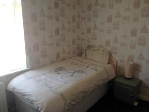 a small bedroom with a bed with writing on it at Liverpool Airport Rooms in Speke