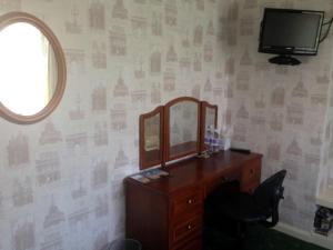 a bedroom with a dresser and a mirror on a wall at Liverpool Airport Rooms in Speke