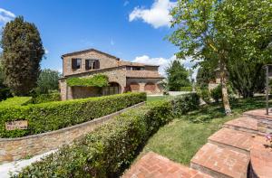 an old stone house with a brick wall and trees at Monti 1824 - Apartments & Cottages in Casole dʼElsa