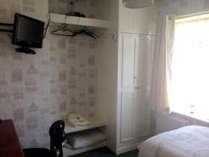 sypialnia z łóżkiem i telewizorem na ścianie w obiekcie Liverpool Airport Rooms w mieście Speke