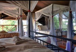 a bedroom with two beds with mosquito netting at Mbali Mbali Tarangire River Camp in Kwa Kuchinia