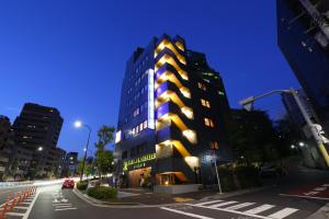 een hoog gebouw in een stadsstraat 's nachts bij Wise Owl Hostels Shibuya in Tokyo