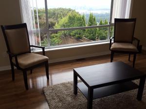 two chairs and a coffee table in a room with a large window at Emperial Suites in North Vancouver
