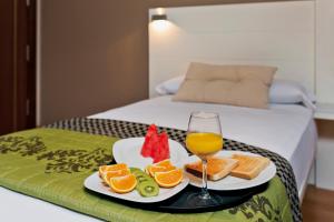 Una bandeja con un plato de fruta y una copa de vino. en Hotel Fuente El Cura, en Sax