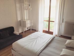 a bedroom with a bed and a couch and a window at Sunny family apartment in villa - HUMANITAS FORUM IEO in Pieve Emanuele