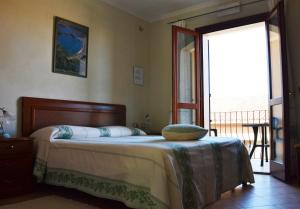 a bedroom with a bed and a door to a balcony at Hotel da Paolino in Trinità d'Agultu e Vignola