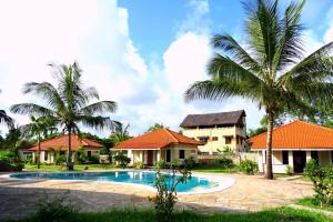 a villa with a swimming pool and palm trees at Doric Cottages Diani in Diani Beach
