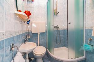 La salle de bains est pourvue de toilettes, d'un lavabo et d'une douche. dans l'établissement Apartmani "Oštro" Crikvenica, à Kraljevica