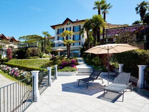 - une terrasse avec 2 chaises et un parasol en face d'un bâtiment dans l'établissement Hotel Belvedere Ranco, à Ranco