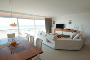 a living room with white furniture and a table and chairs at De Haan - Apartment Silverbeach in De Haan