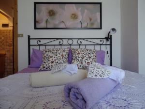 a bed with purple pillows and a picture on the wall at Casa di Fiore in Gaeta