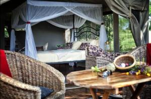 Kwa Kuchinia的住宿－Mbali Mbali Tarangire River Camp，配有一张床和一张桌子及椅子的房间