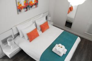 a bedroom with a white bed with orange and blue pillows at Lazuli Sea View Beachfront Ap 254 in Larnaka