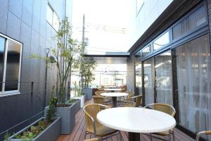un patio al aire libre con mesas, sillas y ventanas en Hotel Showmeikan, en Mishima