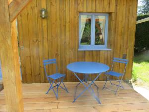 stół i 2 krzesła na ganku kabiny w obiekcie Les Petites Aunettes w mieście Vaubadon
