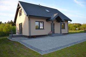 a small white house with a black roof at Dom wakacyjny Albert in Mieroszyno