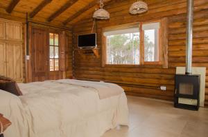Un dormitorio con una cama y un televisor en una habitación. en Cabañas Agalma, en Villa Yacanto