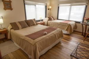 a hotel room with two beds and two windows at Weisserhaus in Puerto Varas