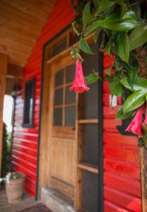 una casa roja con una puerta roja y algunas flores en Weisserhaus, en Puerto Varas