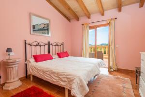 a bedroom with pink walls and a bed with red pillows at Can Canals in Artá +26 photos
