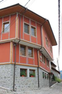 un edificio rojo con ventanas laterales en Guest House Maria en Koprivshtitsa