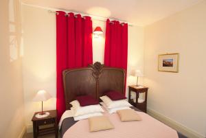 a bedroom with a bed with red curtains at Maison d'Hotes Orlaya in Assier