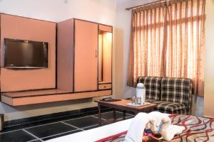 a hotel room with a bed and a tv and a chair at Hotel Laxmi Palace in Udaipur