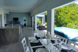a dining room with a table and a swimming pool at Lotus Villa in Bois dʼOrange