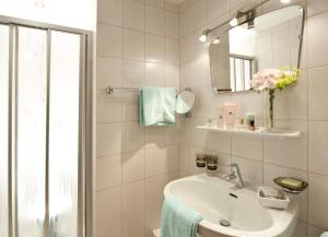 a white bathroom with a sink and a mirror at Hotel Antony in Ischgl +20 photos