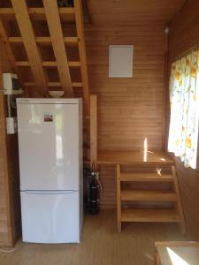 a white refrigerator in a room with wooden walls at Melluzi chalet in Jūrmala