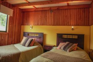 Duas camas num quarto com paredes com painéis de madeira em Cabañas Palafitos Los Pescadores em Castro