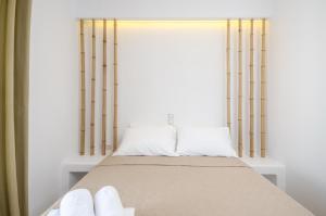 ein Bett mit zwei weißen Kissen und einem Fenster in der Unterkunft Aphrodite Luxury Apartments in Agios Prokopios