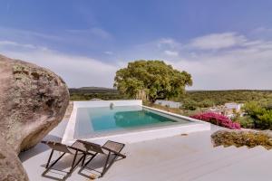 a swimming pool with two chairs and a table at Monte Velho Equo-Resort in Arraiolos