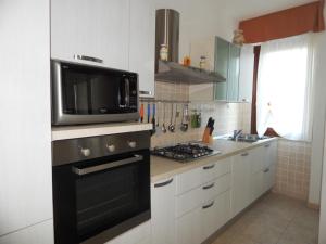 y cocina con microondas y fogones. horno superior en AffittaSardegna-TRILO GEMELLI 2 en Alguer