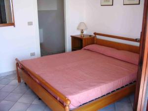 a bedroom with a wooden bed with a red blanket at AffittaSardegna-Villetta Trilo Janna in Stintino