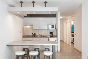 a kitchen with white cabinets and bar stools at Aparthotel Los Dragos del Sur in Puerto de Santiago