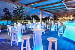 um restaurante com mesas brancas e bancos num deque em Elba Premium Suites - Adults Only em Playa Blanca