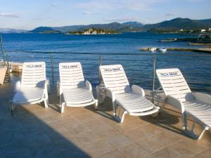 une rangée de chaises blanches assises sur une terrasse près de l'eau dans l'établissement Apartments Deak, à Janjina