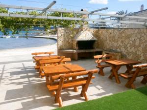 a group of wooden tables and benches next to the beach at Apartments Deak in Janjina
