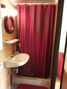 a bathroom with a red shower curtain and a sink at Magdaléna Vendégház in Bük