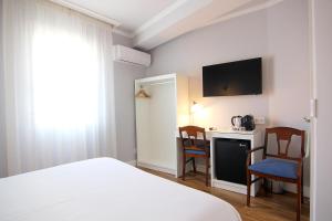 a bedroom with a bed and a desk with chairs at Hostal Los Castañuelos in Candeleda