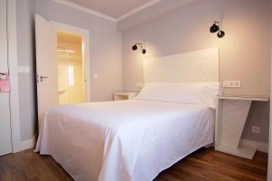 a bedroom with a large white bed and a mirror at Hostal Los Castañuelos in Candeleda