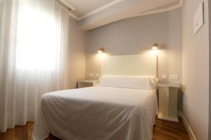 1 dormitorio con cama blanca y ventana en Hostal Los Castañuelos en Candeleda