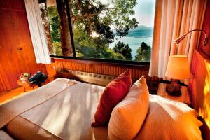 a bed in a room with a large window at Hotel Antumalal in Pucón