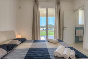 a large bed in a bedroom with a large window at Il Giardino dei Frangipani in Santa Croce Camerina