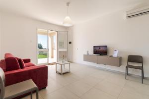a living room with a red couch and a tv at Il Giardino dei Frangipani in Santa Croce Camerina
