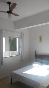 Avila Hotel في بوا إسبيرانسا: غرفة بيضاء مع سرير ومروحة سقف
