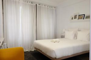 1 dormitorio con cama blanca y cortinas blancas en Koka's Studio, en Oporto